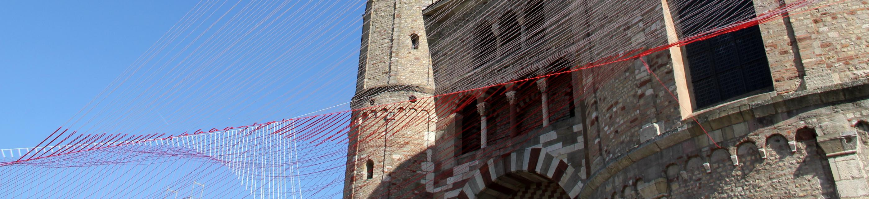 Blick von unten auf den Trierer Dom. Am Dom ist ein Netz vor den blauen Himmel gespannt