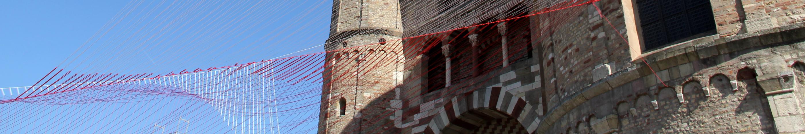 Blick von unten auf den Trierer Dom. Am Dom ist ein Netz vor den blauen Himmel gespannt